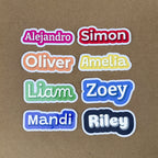 A grid of eight 4-inch wide custom vinyl name stickers showcasing a variety of fonts and colors, including pink (Alejandro), red (Simon), orange (Oliver), yellow (Amelia), green (Liam), blue (Zoey), purple (Mandi), and black (Riley).