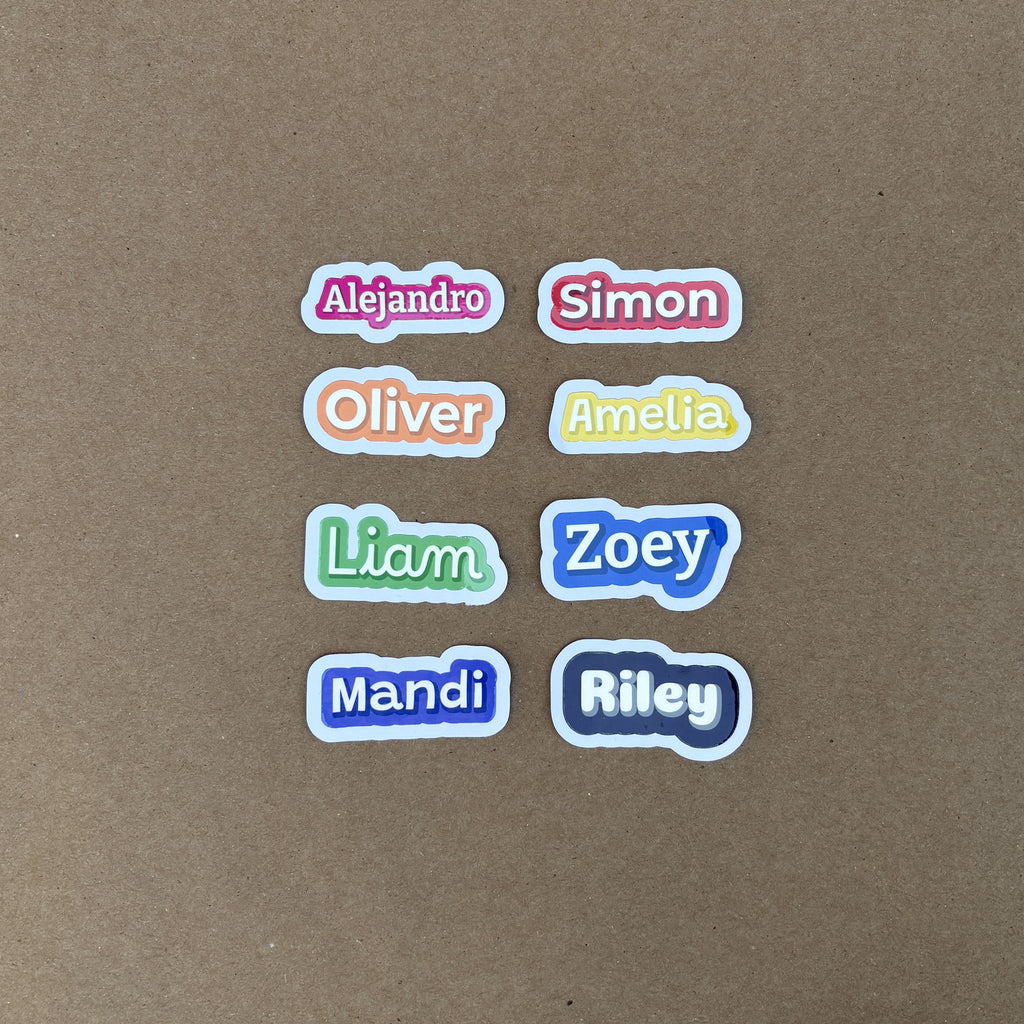 A grid of eight 2-inch wide custom name stickers showcasing all available colors, including red (Simon), orange (Oliver), and purple (Mandi).